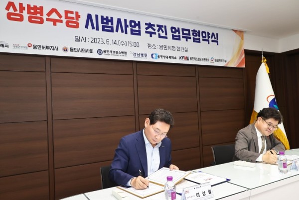 7-2. 14일 용인시청에서 열린 용인특례시 상병수당 2단계 시범사업 업무협약 체결식에서 이상일 용인특례시장(왼쪽)이 협약서에 사인하고 있다..jpg
